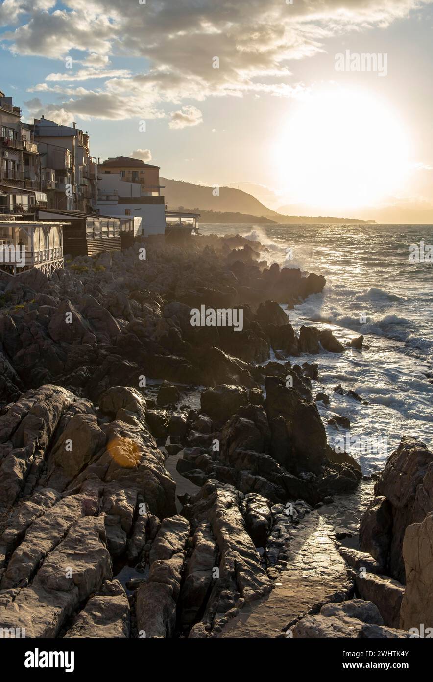 L'acqua di mare si schianta contro le scogliere della costa frastagliata nella città di Cefalù, Sicilia, Italia Foto Stock