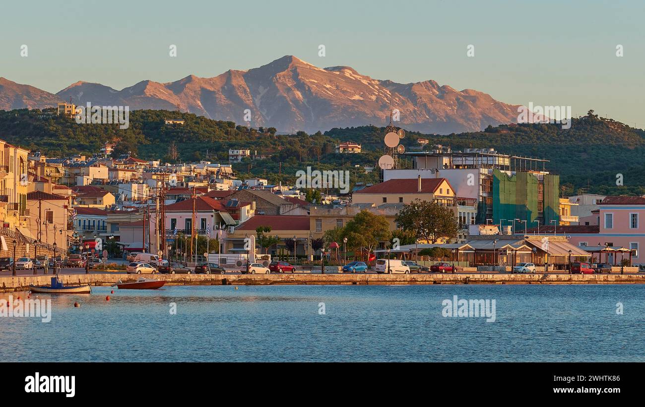 Il sole serale illumina una pittoresca cittadina portuale sul mare con montagne sullo sfondo, i monti Taygetos, Taygetos, Gythio, mani Foto Stock
