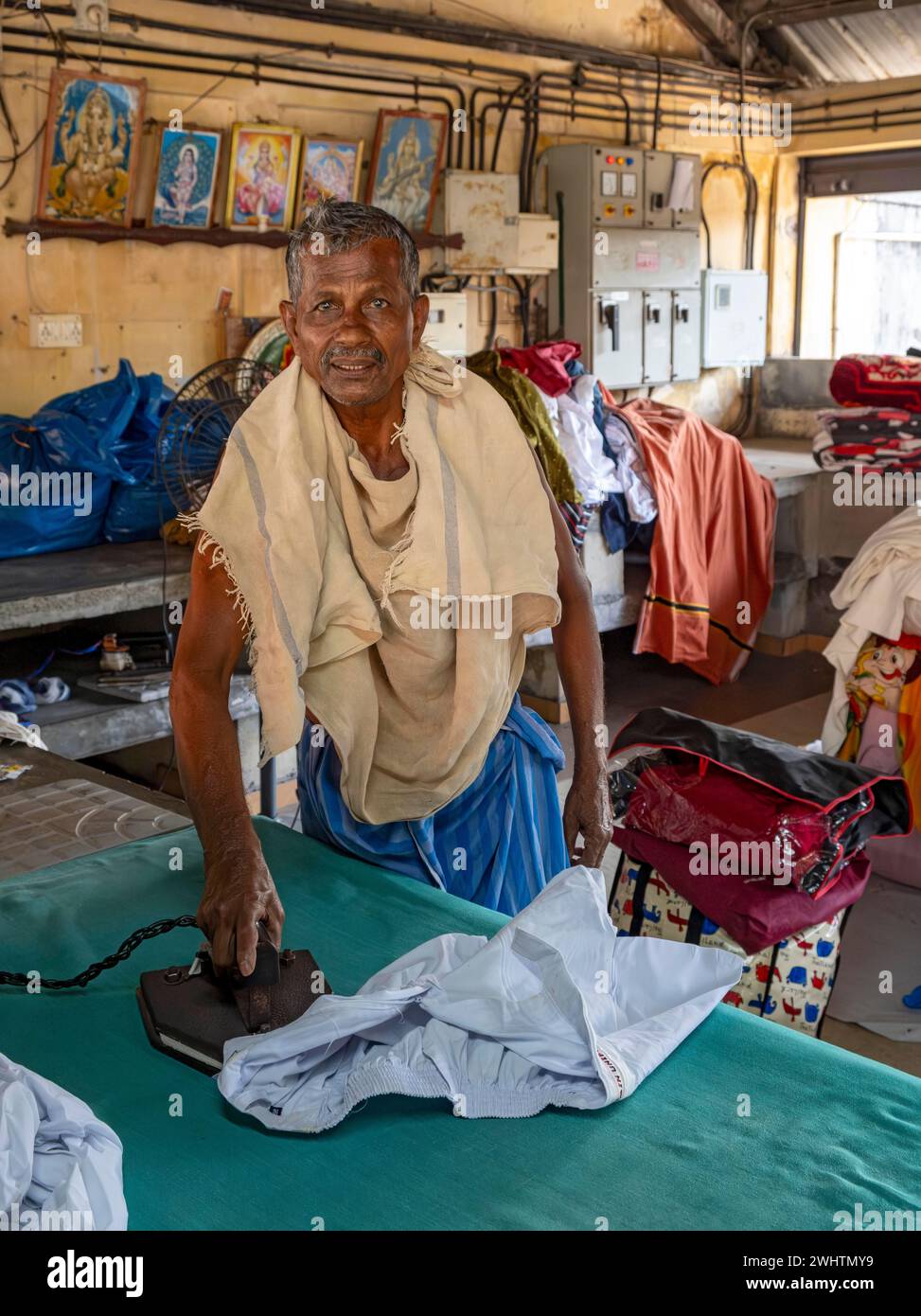 Un uomo stirerà le camicie con un ferro antico al Dhobi Khana Public Laundry, Fort Kochi, Cochin, Kerala, India Foto Stock