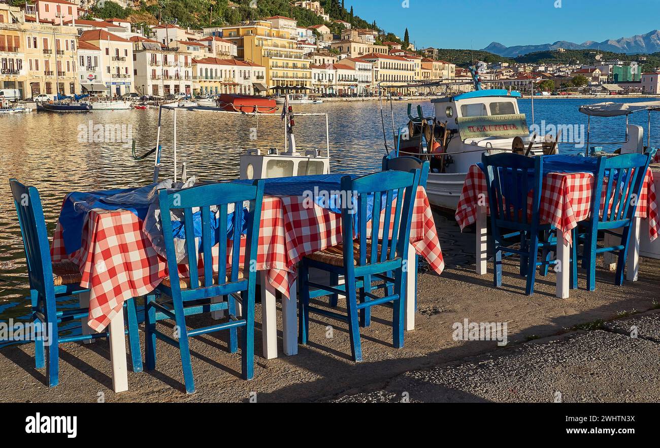 Area esterna di una taverna con vista mare, tovaglie e barche rosse e bianche, Gythio, mani, Peloponneso, Grecia Foto Stock