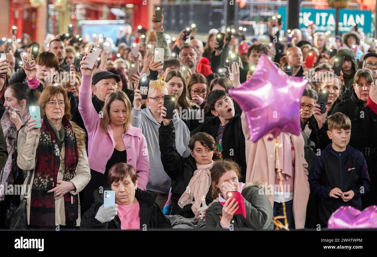 Persone che tengono i loro telefoni in alto durante un silenzio di due minuti alla veglia nella Golden Square, Warrington, per celebrare il primo anniversario dell'omicidio della sedicenne Brianna Ghey. Data foto: Domenica 11 febbraio 2024. Foto Stock