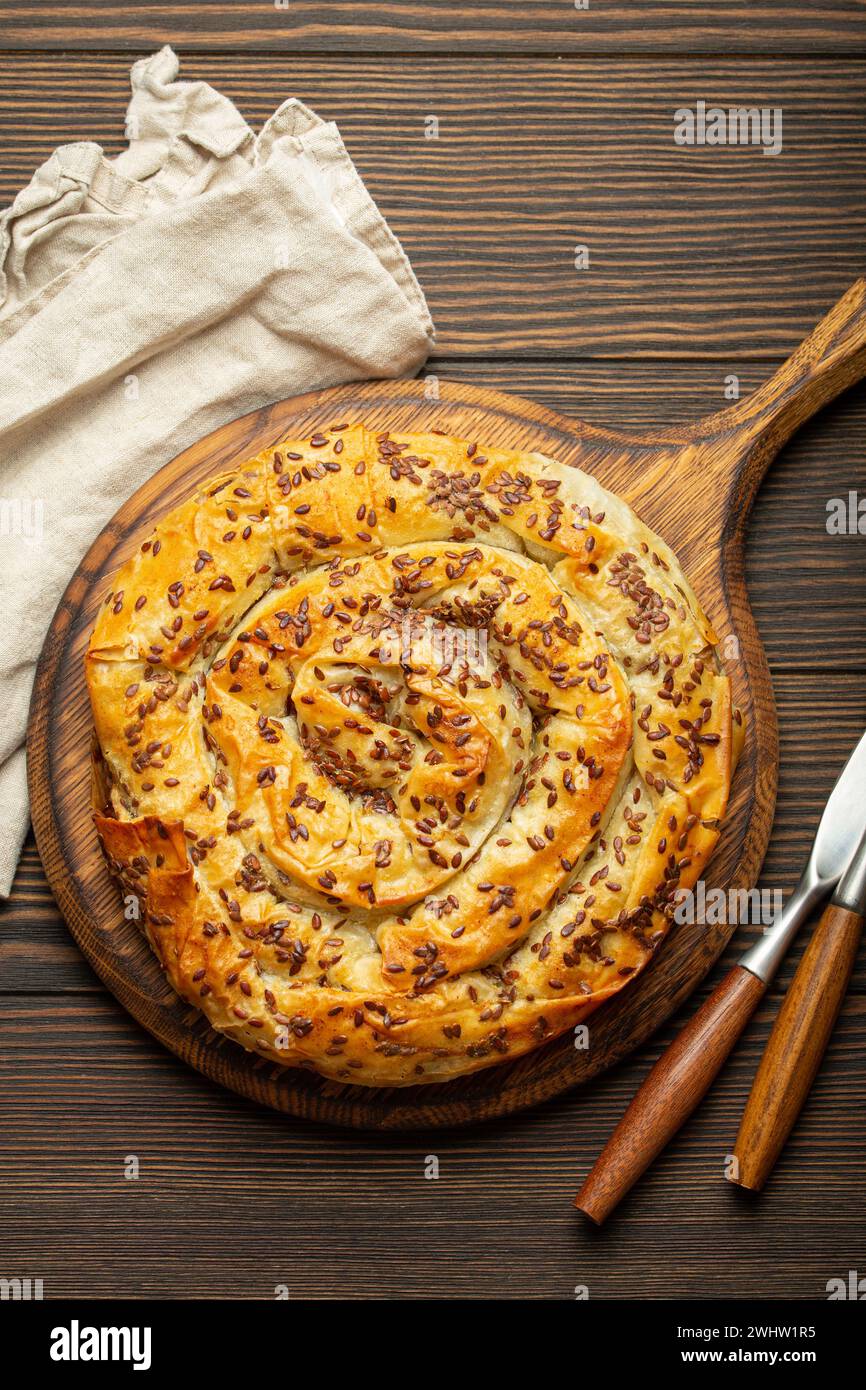 Buretta in pasta fillo con ripieno sul tagliere, vista dall'alto in legno rustico marrone scuro. spir salato tradizionale Foto Stock