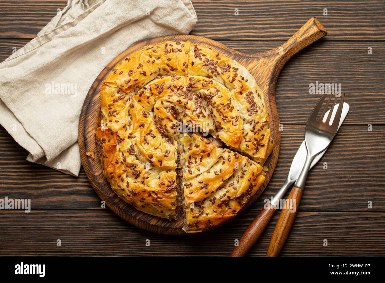 Buretta con pezzo tagliato in pasta filla con ripieno sul tagliere, vista dall'alto in legno rustico marrone scuro. Tradizionale Foto Stock