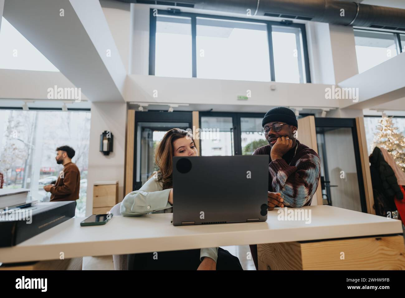 Due giovani professionisti, un uomo e una donna, che collaborano con entusiasmo e concentrazione in un moderno ufficio. Foto Stock