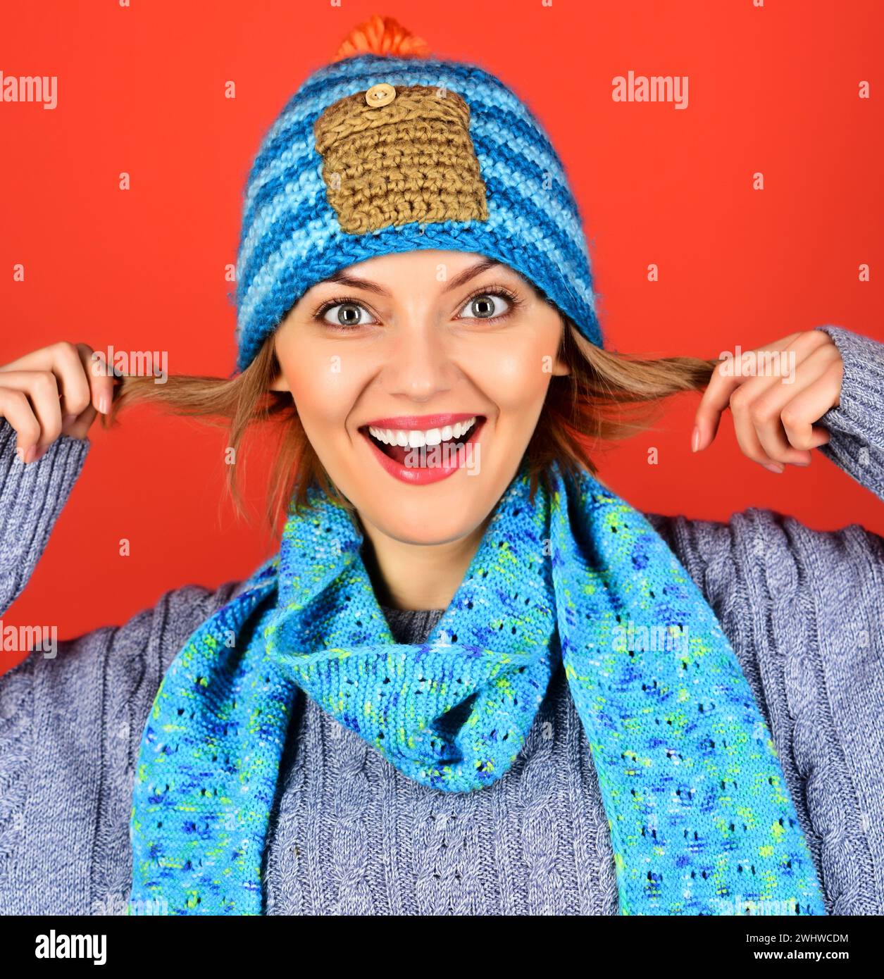 Ritratto di una bella donna con cappello, sciarpa e maglione a maglia. Ragazza sorridente in abiti invernali. Moda autunno-inverno femminile. Donna emotiva dentro Foto Stock