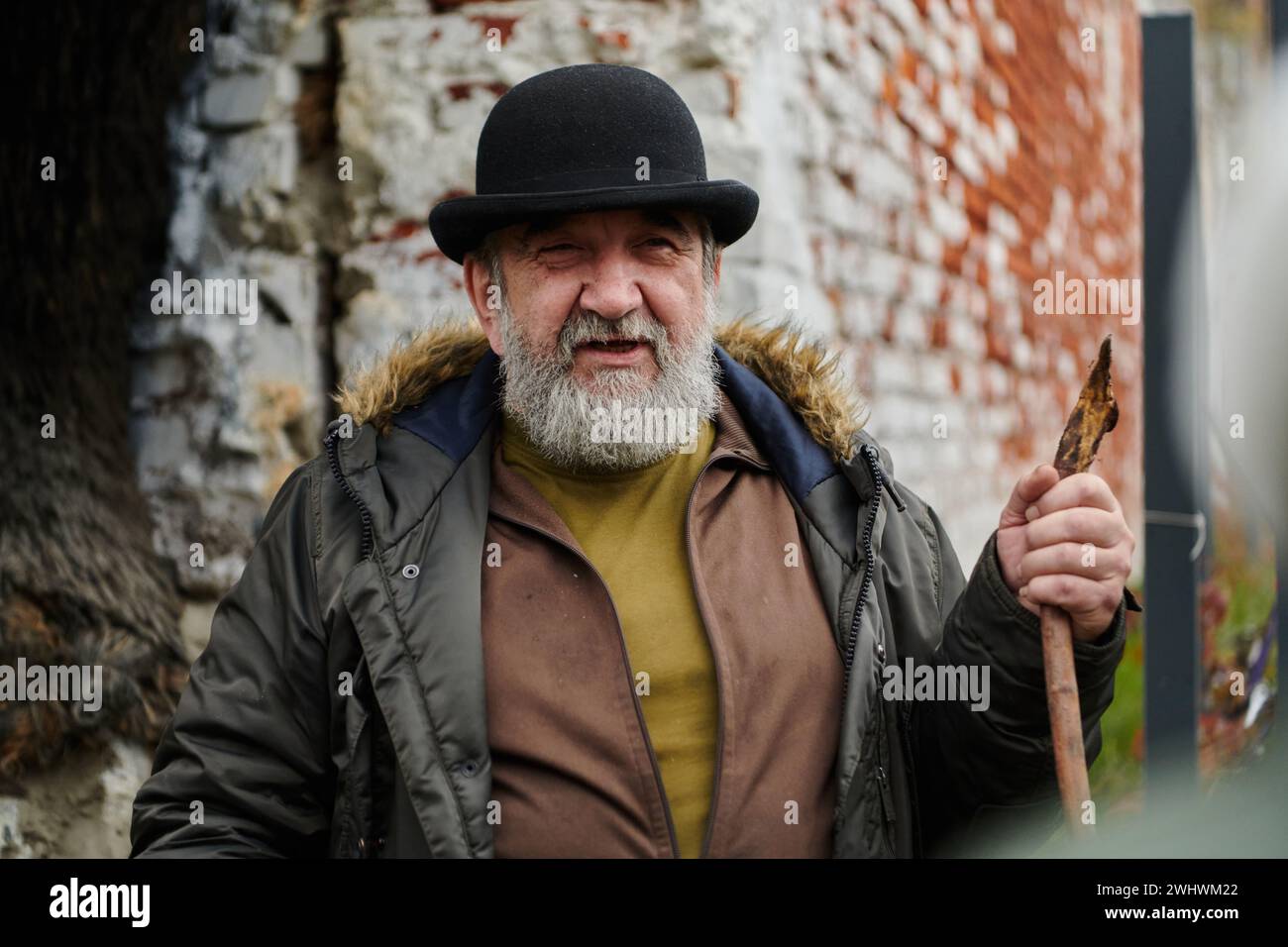 Un uomo anziano con la barba e un cappello indossato trasmette con passione i valori tradizionali e la saggezza culturale agli altri, incarnando il Foto Stock