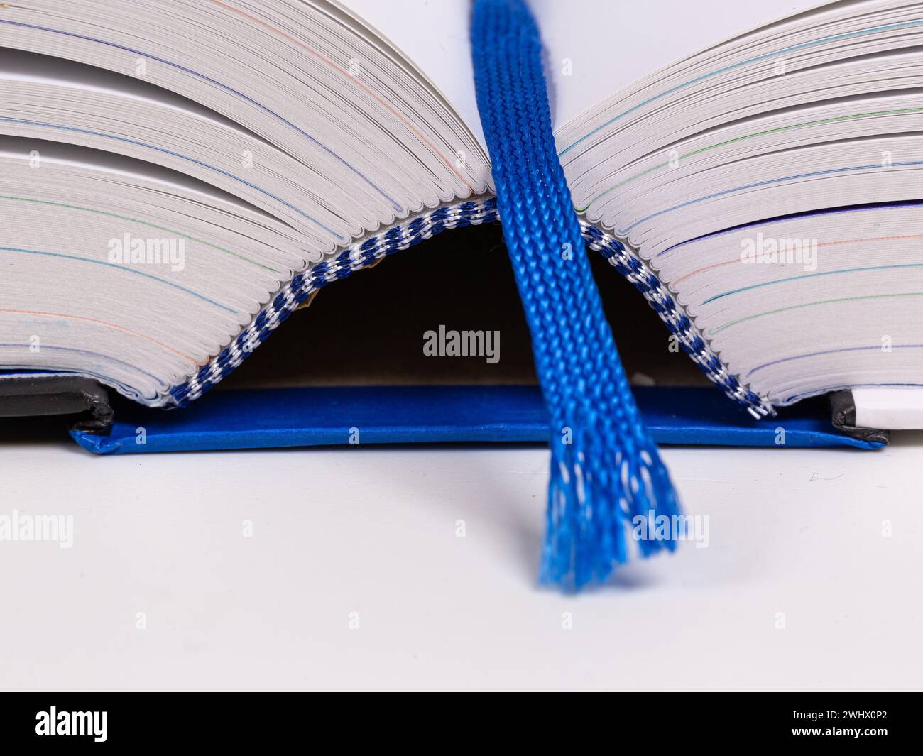 Primo piano di un libro aperto con un nastro di lettura blu, una copertina rigida blu e cuciture con fili blu e bianchi Foto Stock