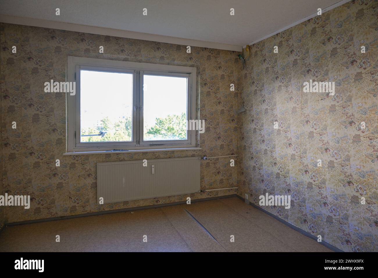 Camera vuota non ristrutturata con una vecchia carta da parati alle pareti, concetto di alloggio e mancanza di spazio abitativo a prezzi accessibili Foto Stock
