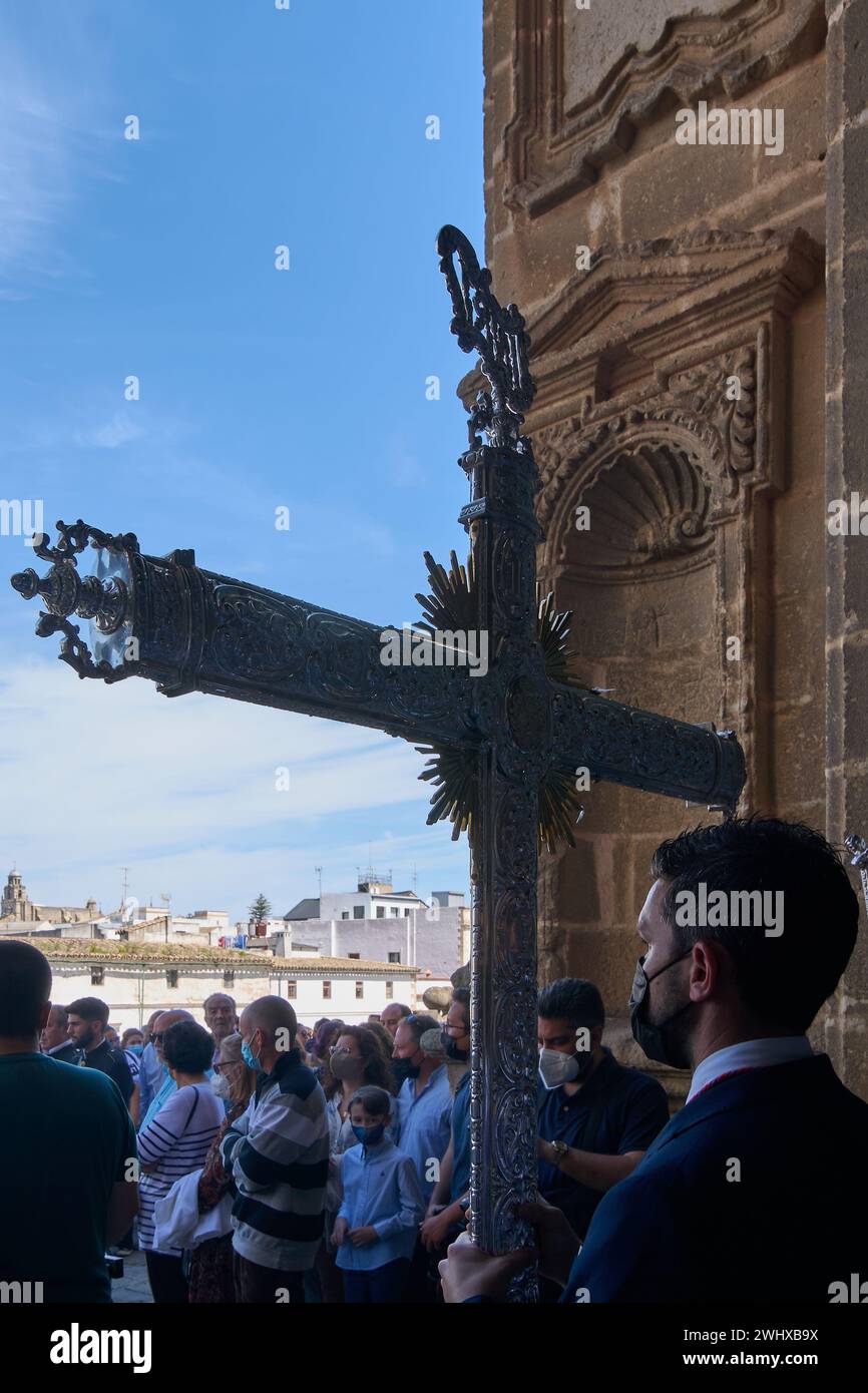Jerez de la Frontera, Spagna - 11 febbraio 2024: Processione religiosa nella settimana Santa, che mostra una croce ornata, adoratori e l'architettura storica Foto Stock