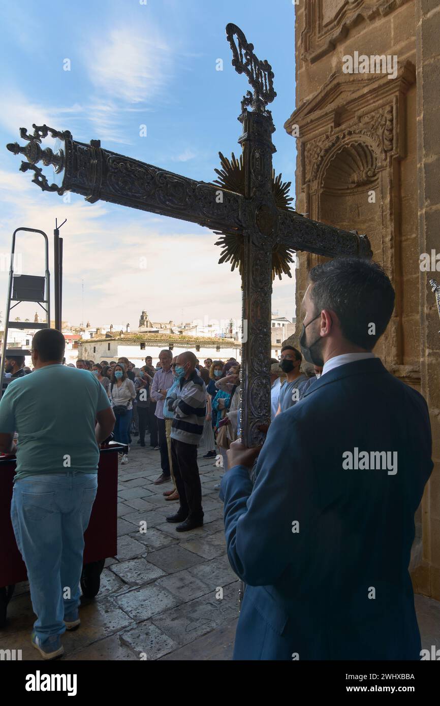 Jerez de la Frontera, Spagna - 11 febbraio 2024: Processione religiosa nella settimana Santa, che mostra una croce ornata, adoratori e l'architettura storica Foto Stock