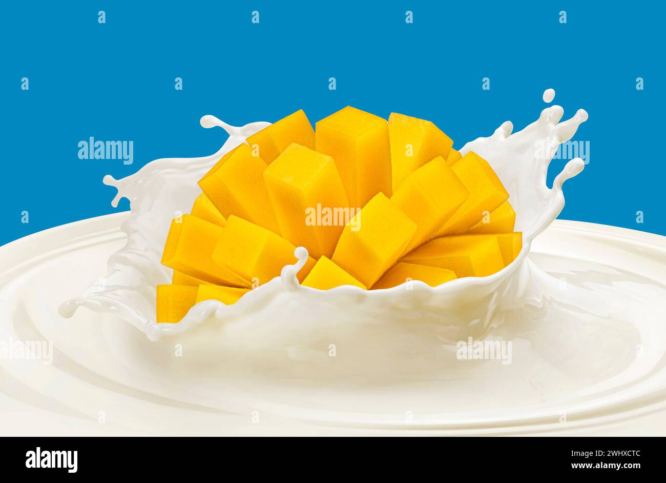 Mango che cade in schizzi di latte isolato su sfondo colorato Foto Stock