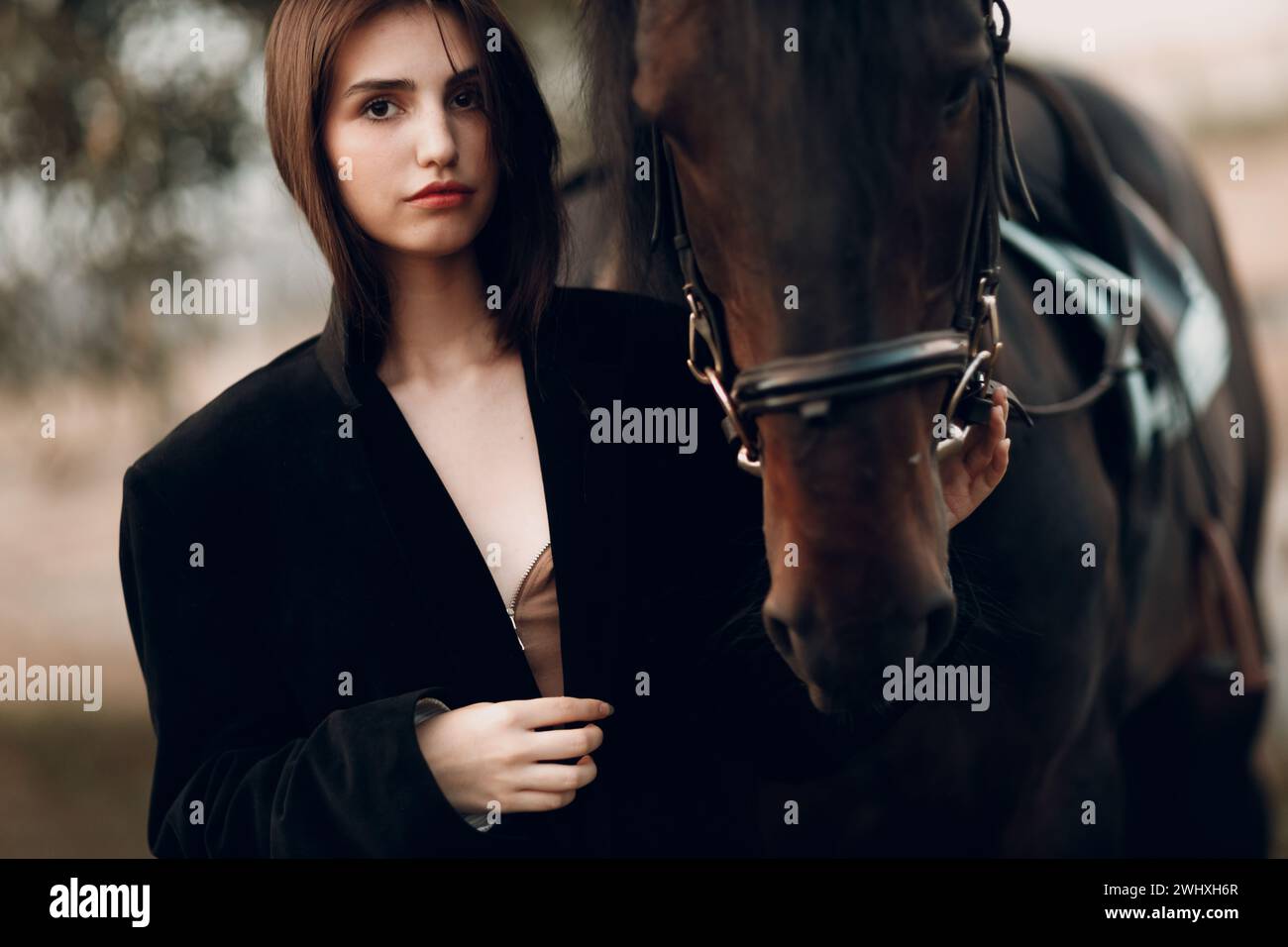 Giovane donna in nero con il suo cavallo al tramonto all'aperto. Foto Stock