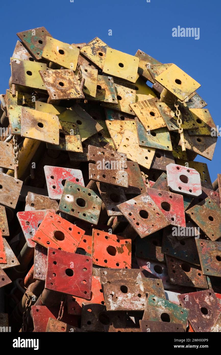 Pile di montanti in acciaio colorato assortiti con piastre di base in un deposito all'aperto. Foto Stock