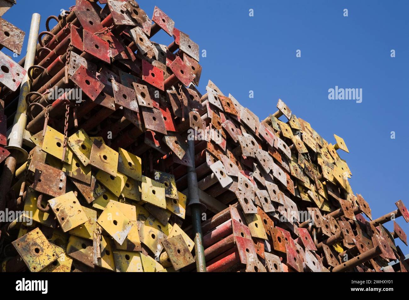Pile di montanti in acciaio colorato assortiti con piastre di base in un deposito all'aperto. Foto Stock