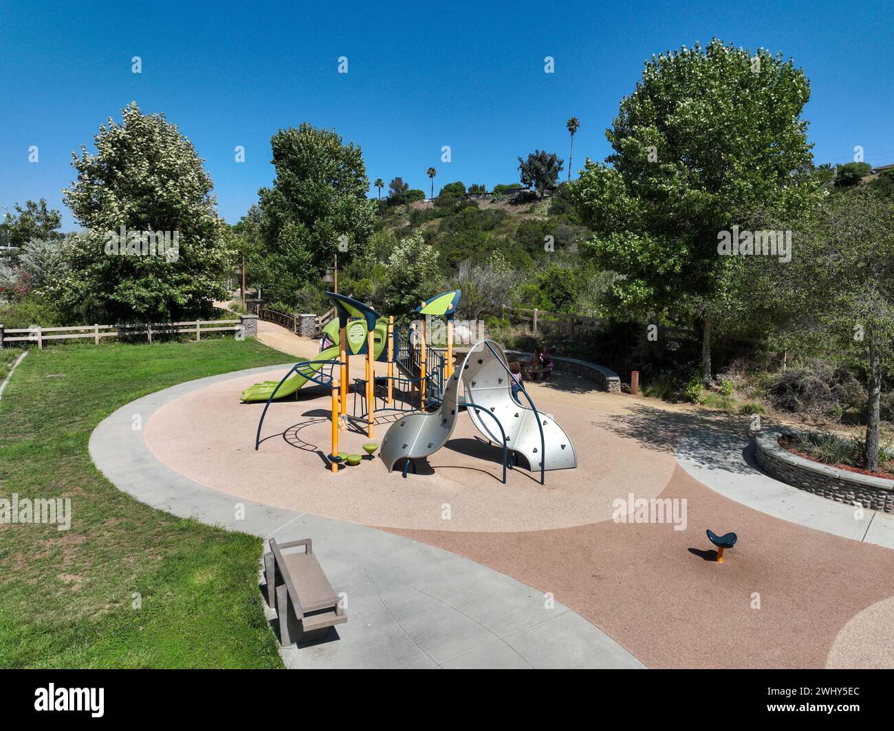 Colorato parco giochi per bambini attività nel parco pubblico circondato da verdi alberi Foto Stock