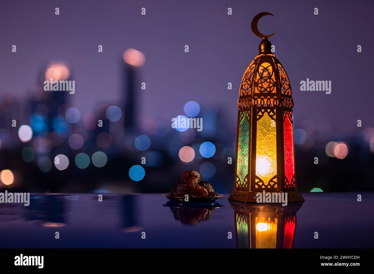 Lanterna e piccolo piatto di datteri frutta con cielo notturno e città bokeh sfondo chiaro per la festa musulmana del mese santo di Ramadan Kareem. Foto Stock