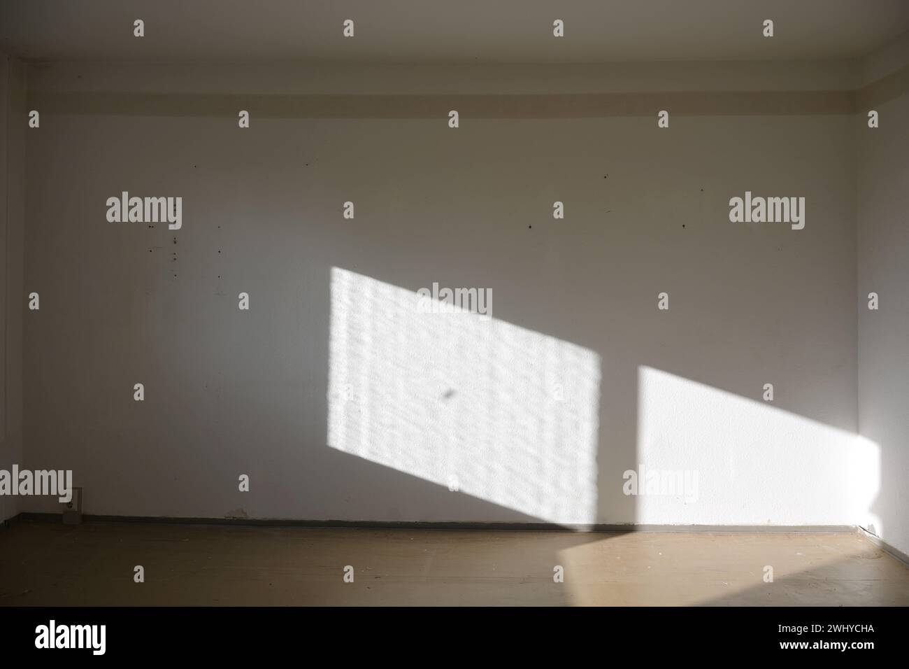 Luce dalla finestra sulla parete di un soggiorno vuoto non rinnovato in un vecchio appartamento pubblico, architettura, ristrutturati Foto Stock