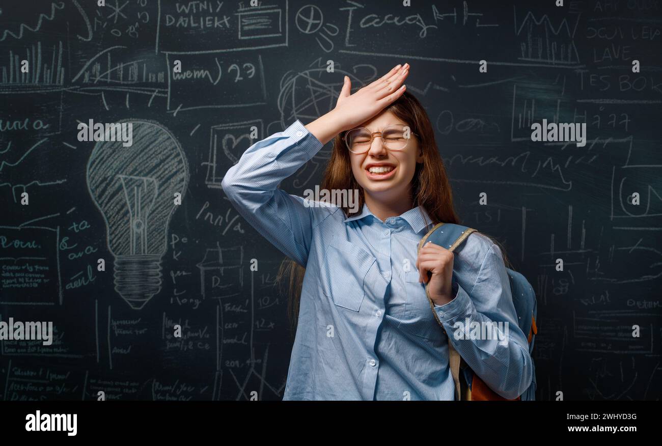 Torna a scuola. Adolescente infelice al chiuso. La ragazza sta imparando in classe sulla lavagna. Foto Stock