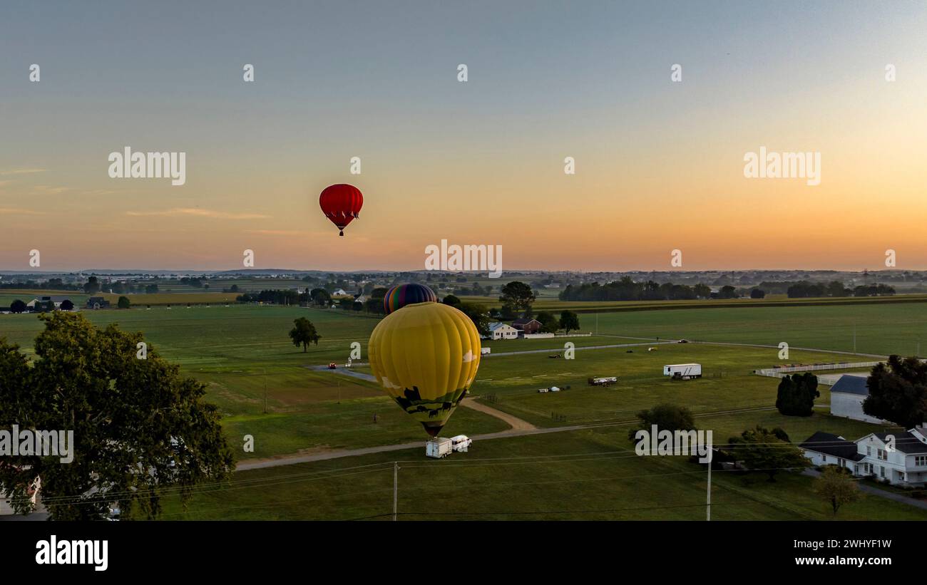 Vista aerea di tre mongolfiere che si preparano al lancio, con una in aria, che galleggia via Foto Stock