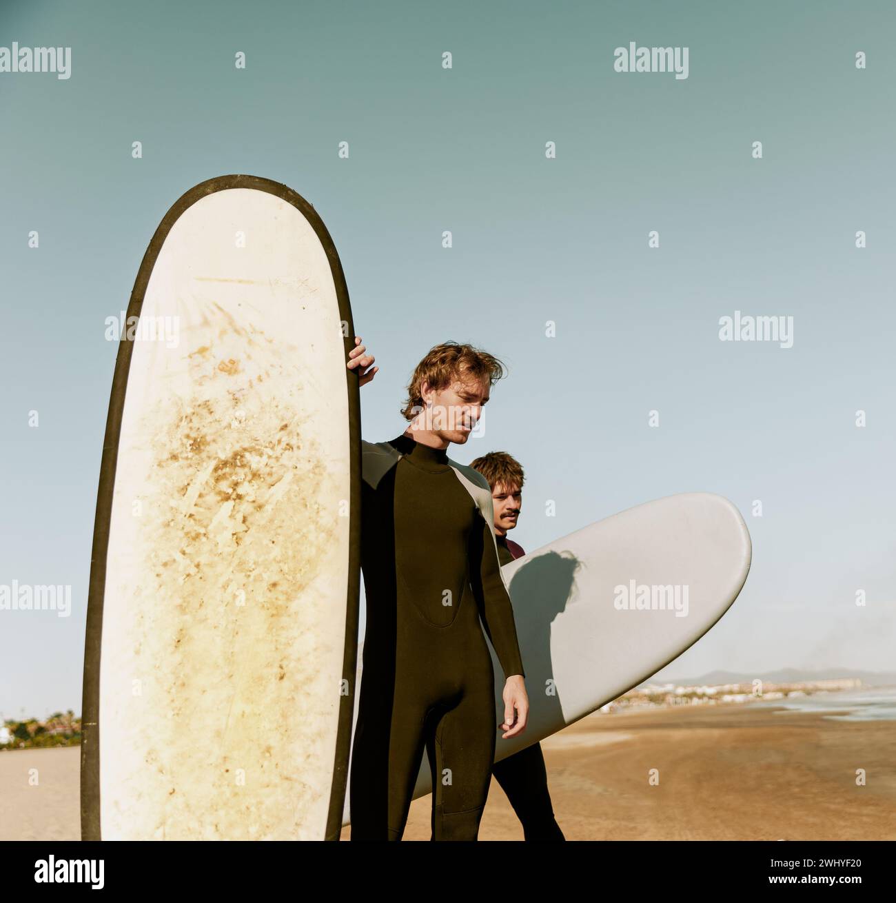 Gruppo di amici surfisti in muta con tavole da surf e si preparano a cavalcare sulle onde Foto Stock