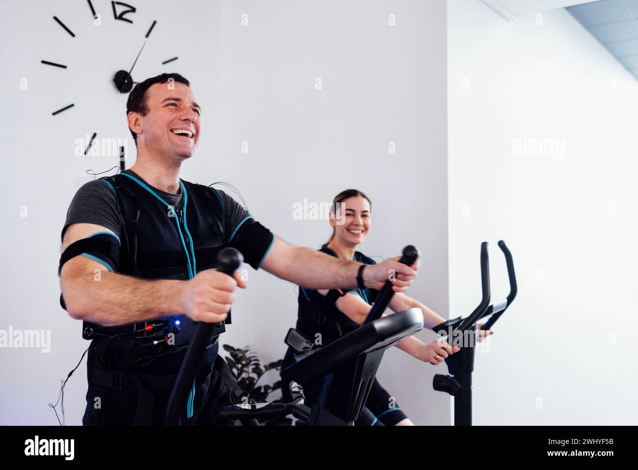 Un paio di sportivi in tute ems sono impegnati in attrezzature sportive nel fitness club o in palestra. Foto Stock