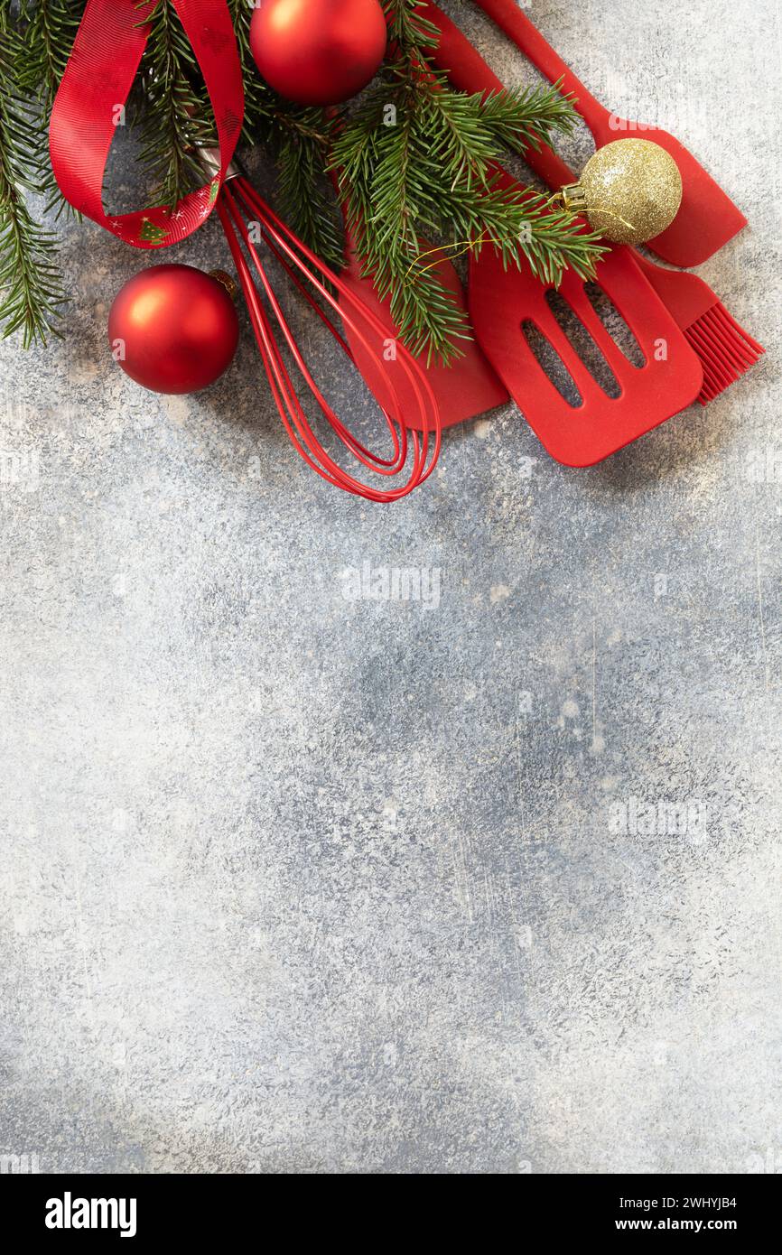 Vari utensili da cucina rossi per il Natale su sfondo in pietra grigia, mockup per la ricetta. Vista dall'alto. Copia spazio. Foto Stock