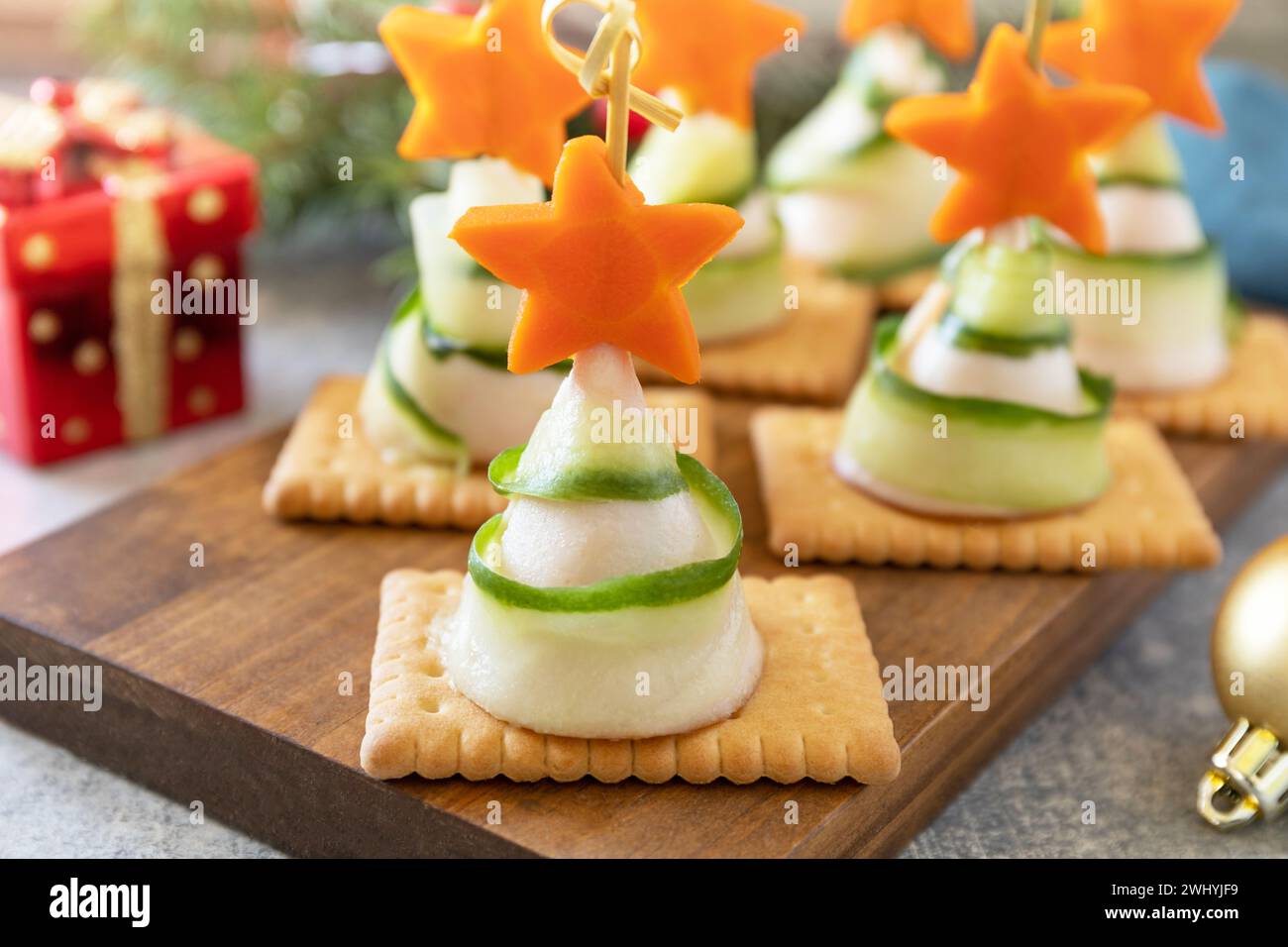 Antipasti creativi di natale. Alberi di Natale di prosciutto, cetriolo, formaggio e stella di carota sui cracker sul tavolo delle feste. Foto Stock