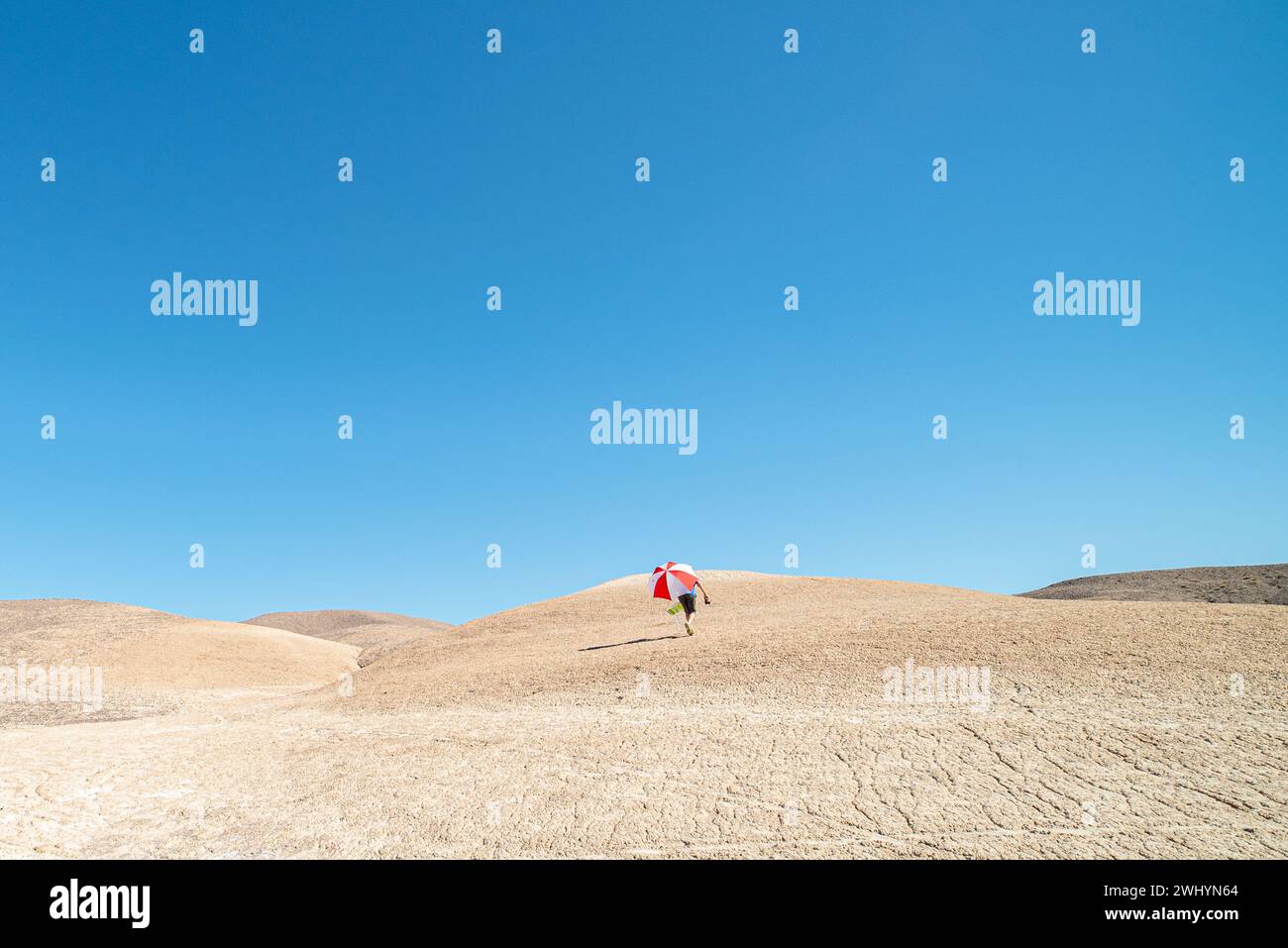 Isolato, uomo, passeggiate, dune di sabbia, ombrello rosso, ombrello bianco, solitudine, paesaggio del deserto, viaggio, avventura Foto Stock
