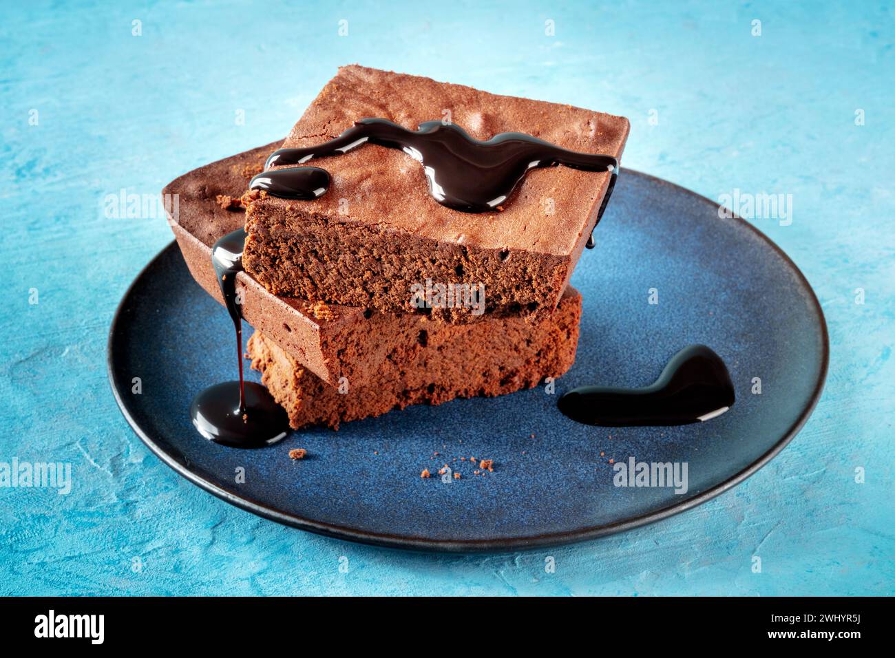 Brownie al cioccolato con salsa allo sciroppo, semplice torta al caffè, su blu Foto Stock