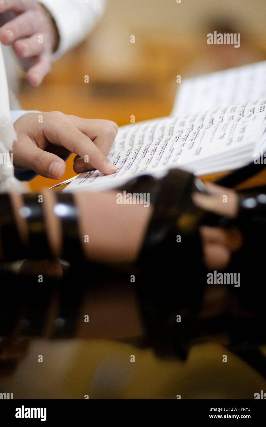 Giovane che pratica la lettura della Torah prima della celebrazione di Bar Mitzvah. Indossare Tefillin sulla mano destra. Foto Stock