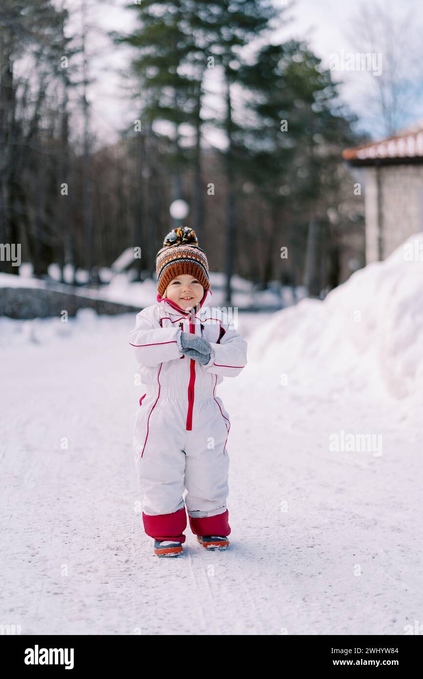 Una bambina sorridente si trova su una strada innevata nella foresta Foto Stock