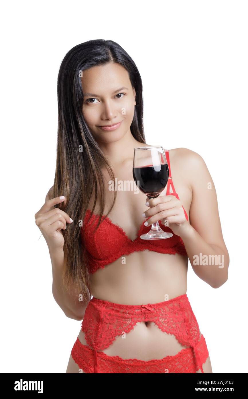 Giovane donna asiatica che indossa lingerie rosse e regge un bicchiere di vino rosso isolato su uno sfondo bianco con spazio per le copie Foto Stock