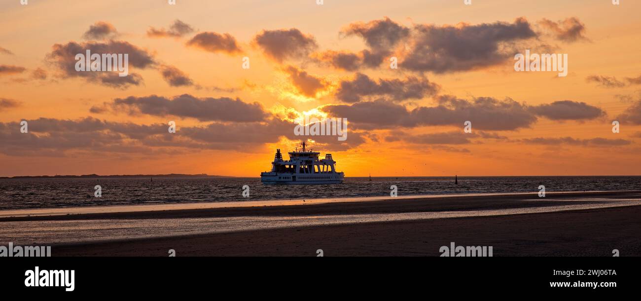Paesaggio pianeggiante con sole al tramonto e traghetto Frisia, Isola di Norderney, Mare del Nord, Germania, Europa Foto Stock