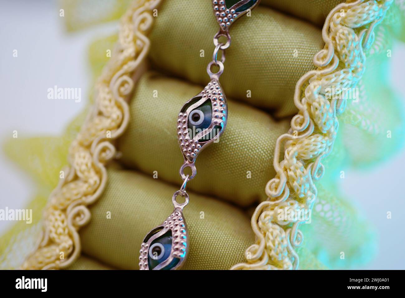 Una vivace collana con perline adorna una delicata tovaglia in pizzo Foto Stock