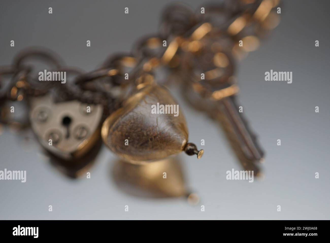 Una serie di chiavi e una catena collocate su un tavolo davanti a un orologio Foto Stock