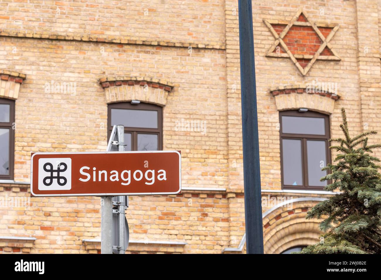 Antica sinagoga in mattoni, shul ebraico o tempio con cartello stradale e stella di David sulla facciata di Alytus, Lituania Foto Stock