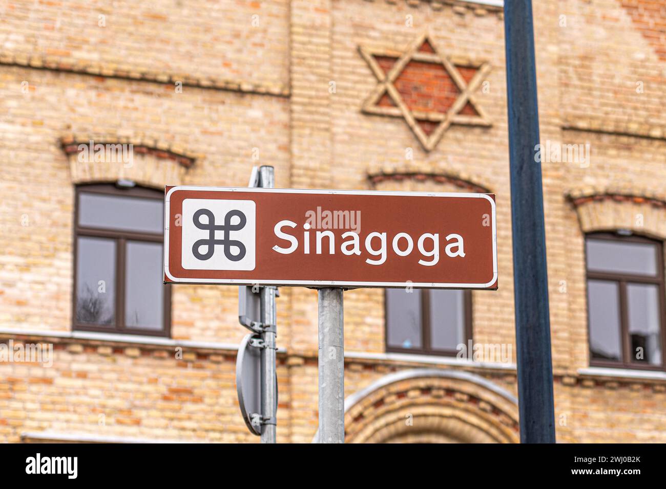 Antica sinagoga in mattoni, shul ebraico o tempio con cartello stradale e stella di David sulla facciata di Alytus, Lituania Foto Stock