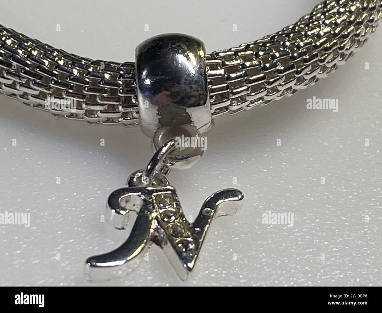 Una perla argentata con la lettera J su un'estremità, a fianco di uno sfondo nero Foto Stock