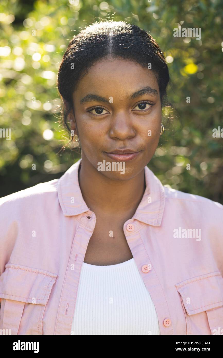 La giovane donna birazziale sta all'aperto, inondata dalla luce del sole Foto Stock