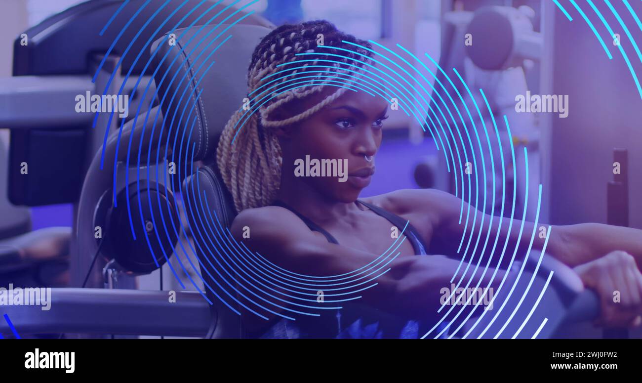 Immagine della spirale blu che ruota sopra una donna afroamericana che si esercita in palestra Foto Stock