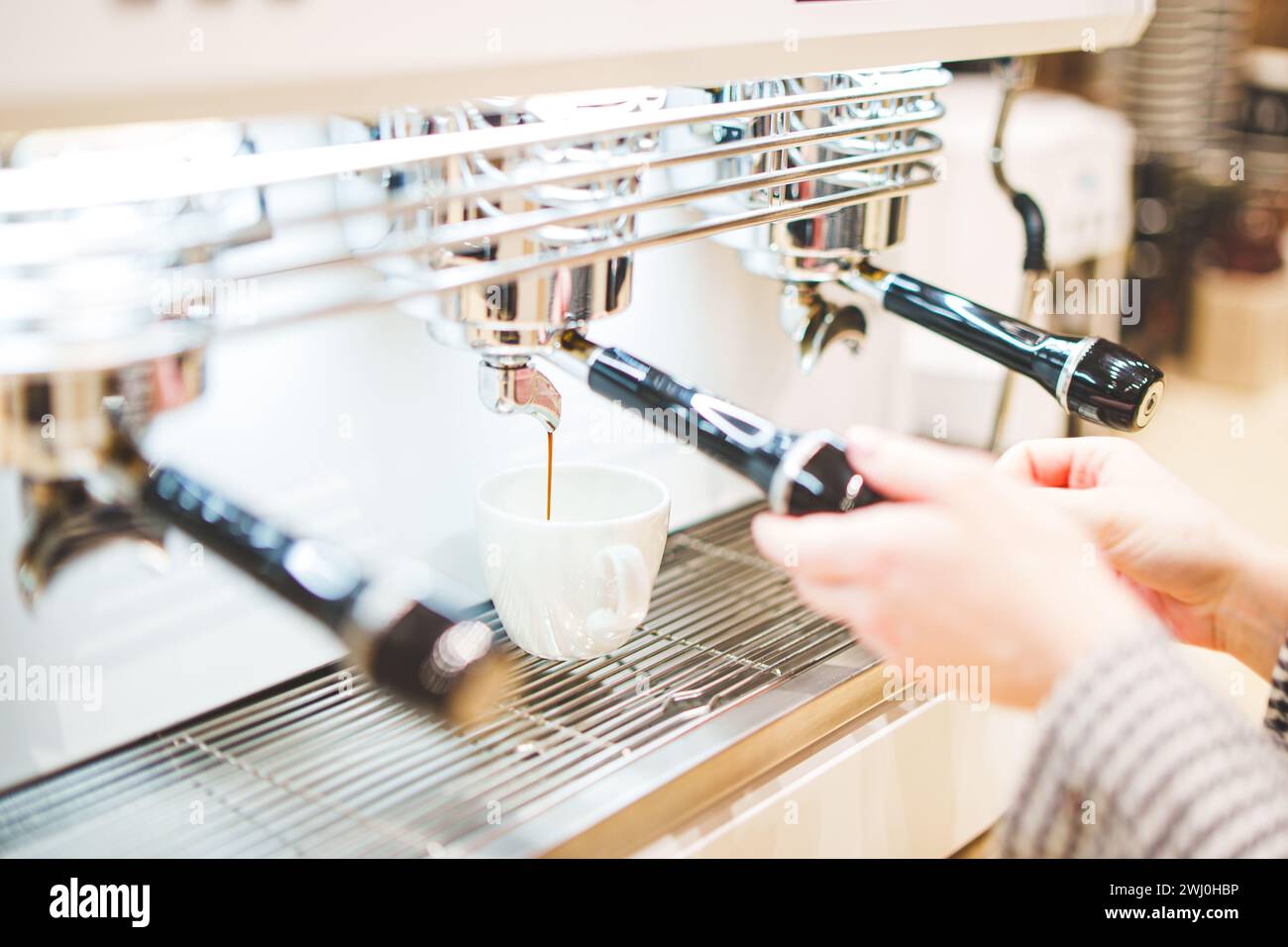 Primo piano del caffè erogato dalla macchina per il caffè. Preparazione professionale del caffè. Foto di alta qualità Foto Stock