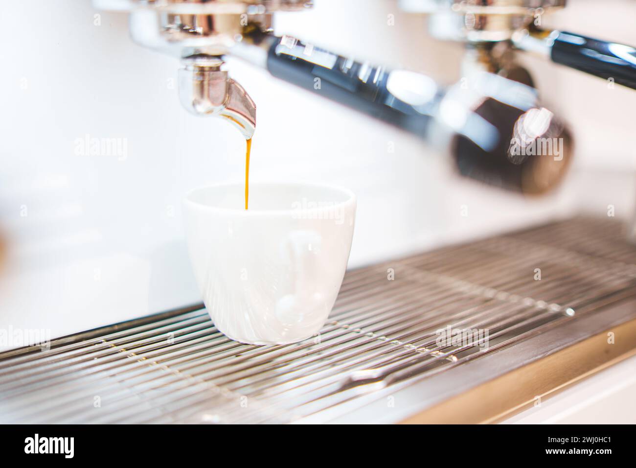 Primo piano del caffè erogato dalla macchina per il caffè. Preparazione professionale del caffè. Foto di alta qualità Foto Stock