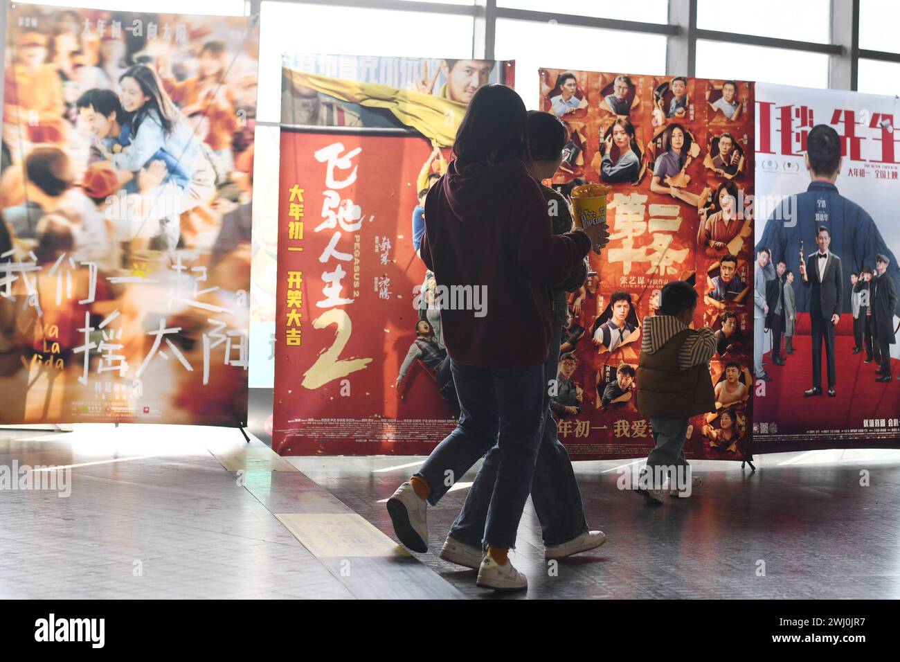 RENHUAI, CINA - 12 FEBBRAIO 2024 - le persone passano accanto ai poster dei film dell'anno lunare cinese al cinema Fenghe nella città di Renhuai, nel sud-ovest della Cina a Guizhou Foto Stock