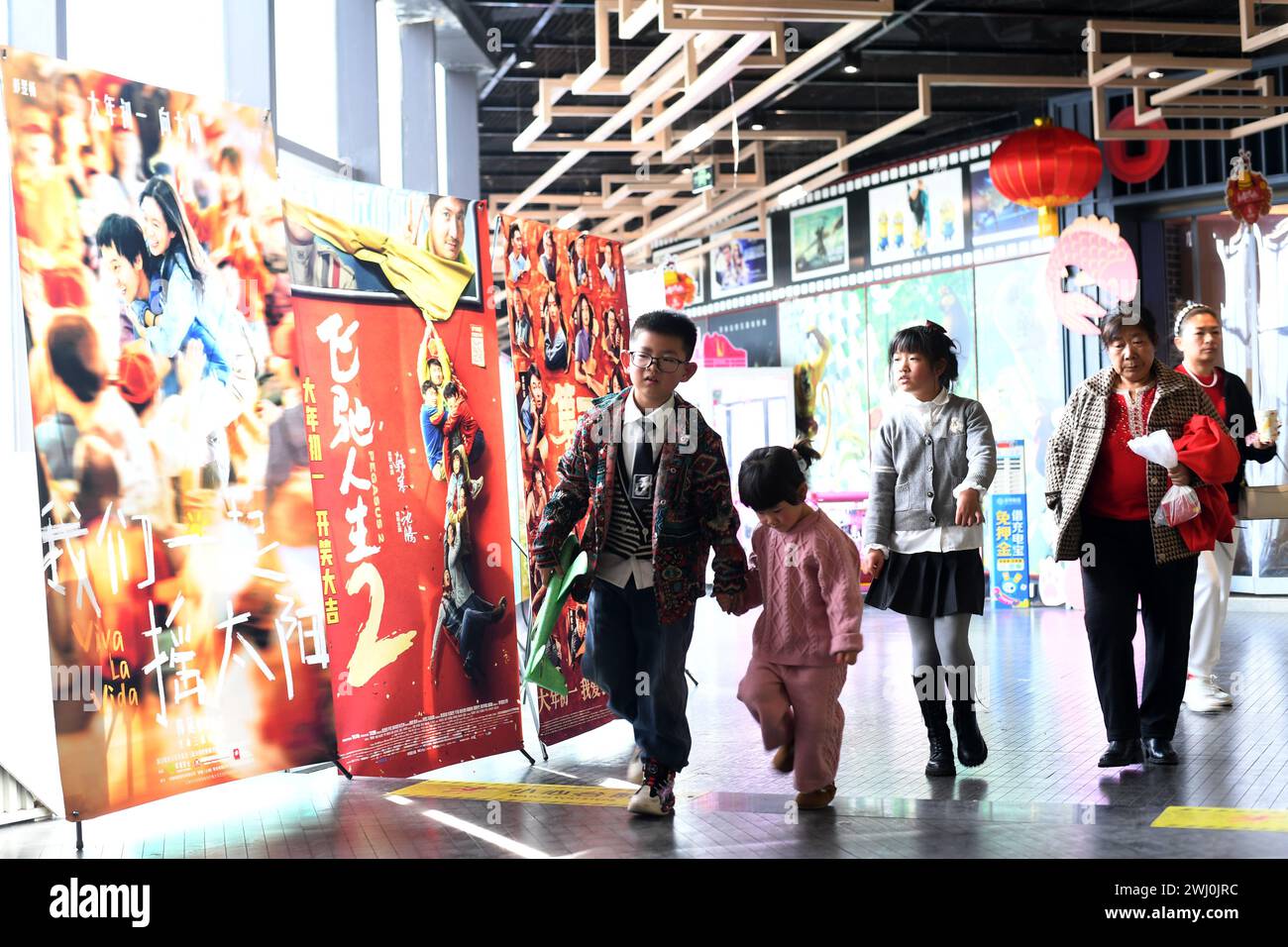 RENHUAI, CINA - 12 FEBBRAIO 2024 - le persone passano accanto ai poster dei film dell'anno lunare cinese al cinema Fenghe nella città di Renhuai, nel sud-ovest della Cina a Guizhou Foto Stock