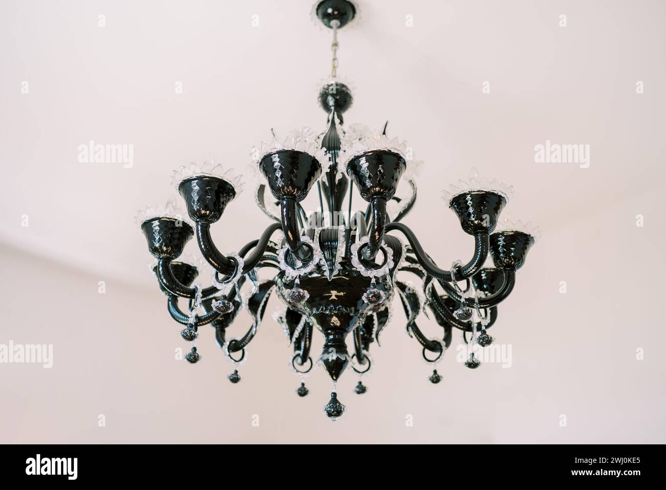 Lampadario nero con decorazioni open work e pendenti appeso al soffitto bianco della villa Foto Stock