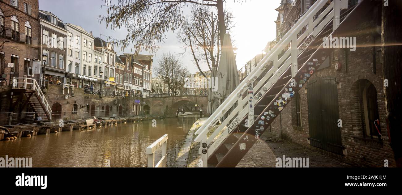 Bagliore di sole nella vista del canale a livello di molo del centro storico della città olandese con negozi lungo il molo a un livello sopra il canale Foto Stock
