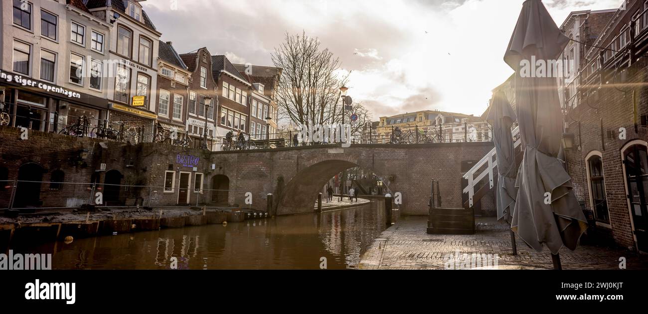 Bagliore di sole nella vista del canale a livello di molo del centro storico della città olandese con negozi lungo il molo a un livello sopra il canale Foto Stock