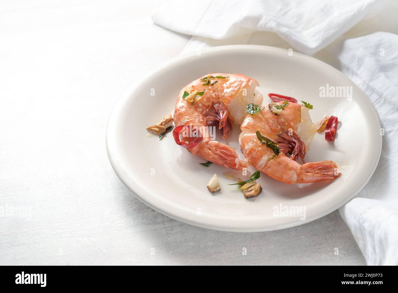 Gamberetti tigre o gamberetti fritti con aglio, erbe e peperoncino rosso serviti su un piatto bianco, piccante piatto gourmet di pesce da f Foto Stock