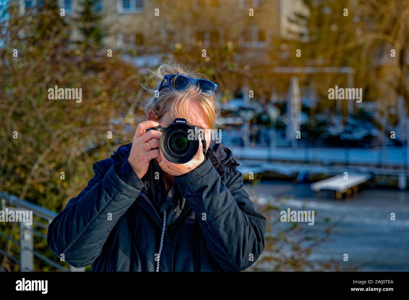 Berlino, Germania - 19 gennaio 2024: Foto frontale di un fotografo in inverno, il cui volto è coperto dalla sua macchina fotografica. Foto Stock
