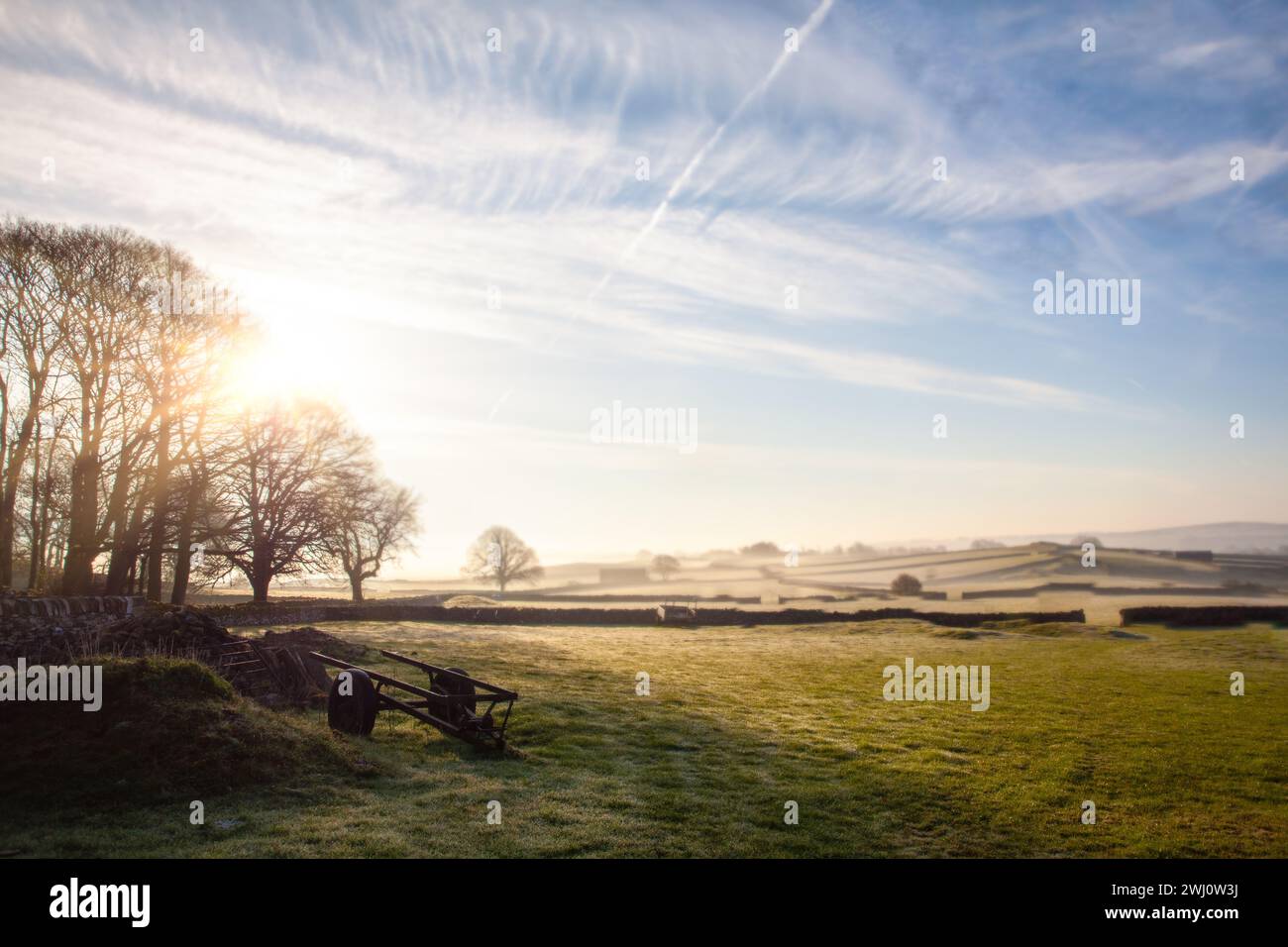 I campi e i muri di pietra sorgono all'alba con un paesaggio di gelo invernale nel Peak District in Inghilterra Foto Stock
